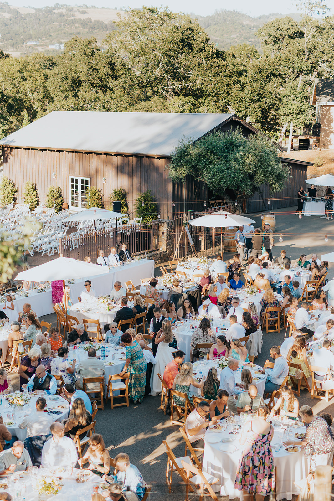 Guests dining at round tables outside the barn